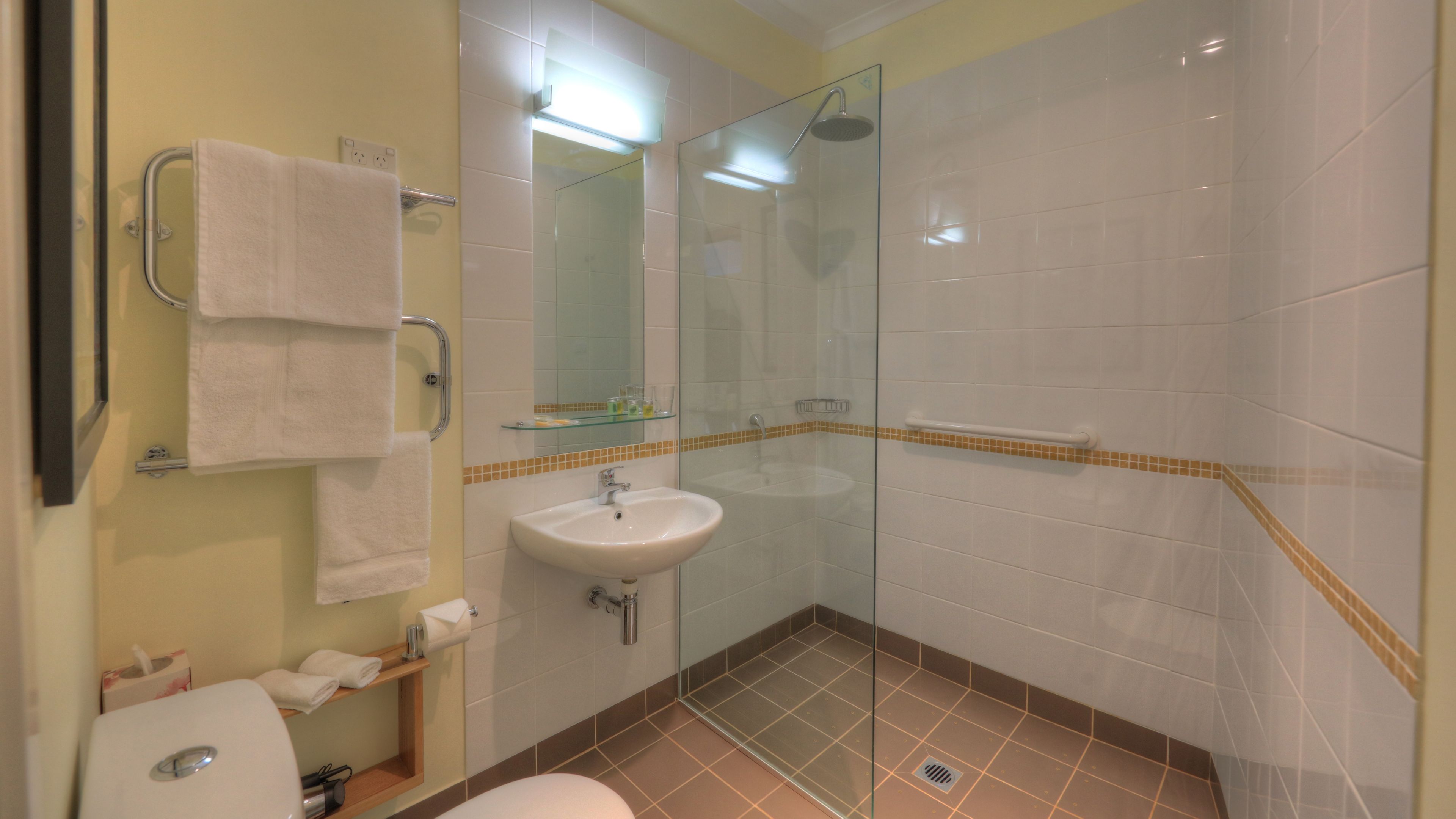 Un baño con ducha de vidrio, lavamanos e inodoro.