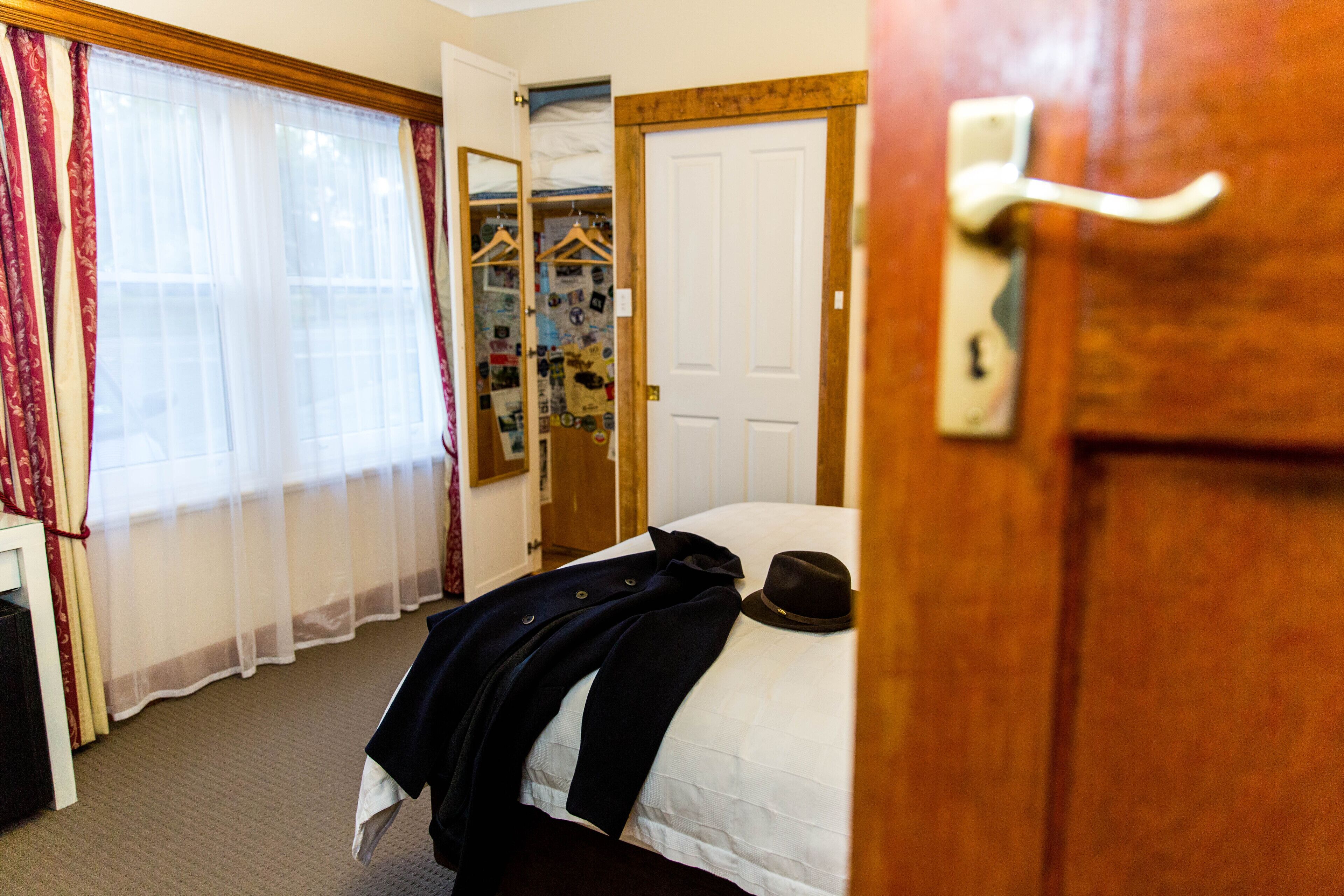 A hotel room with a bed, a wardrobe, and a mirror.