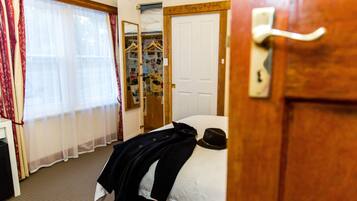 A hotel room with a bed, a wardrobe, and a mirror.