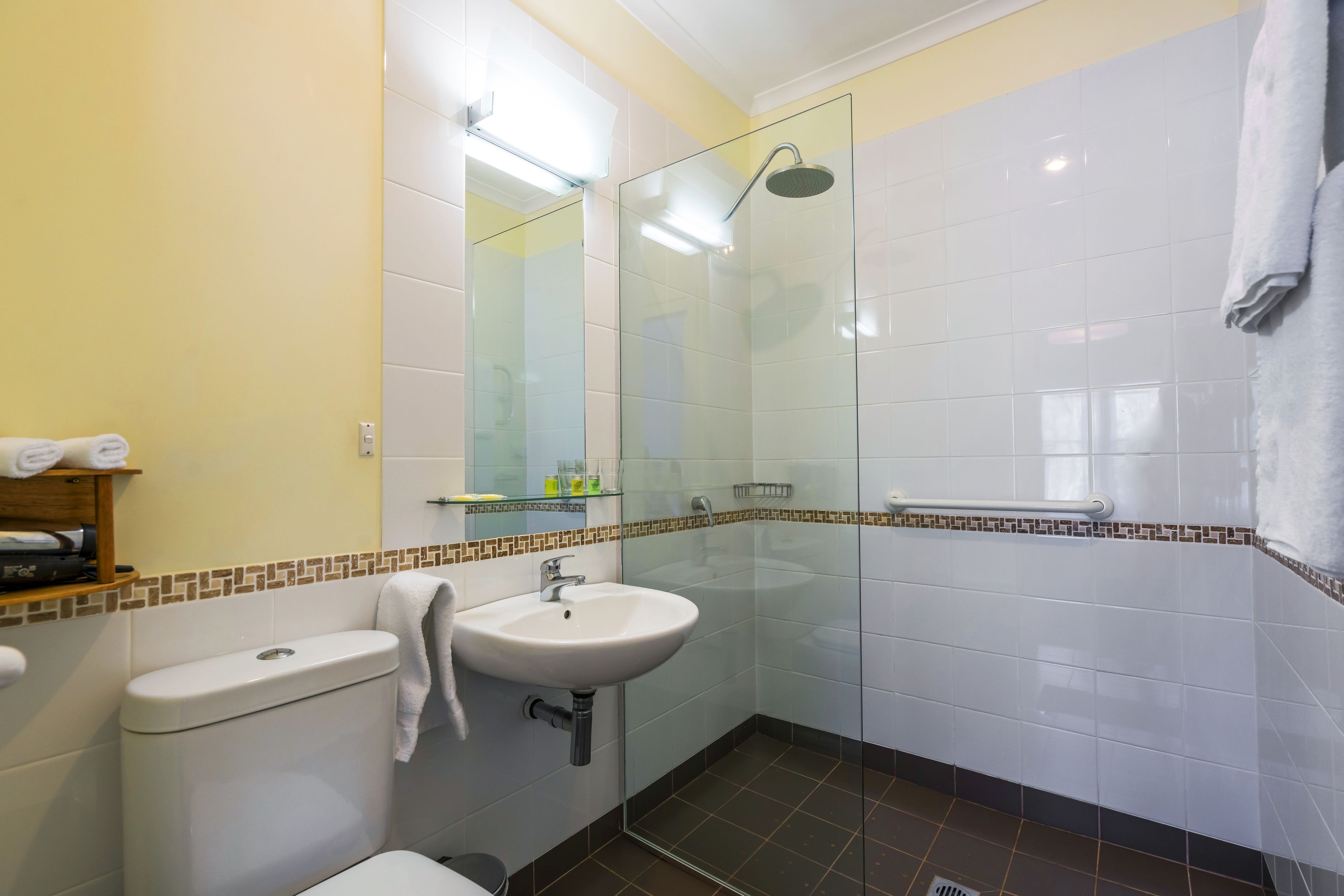 A bathroom with a glass-enclosed shower, a white sink, and a toilet.
