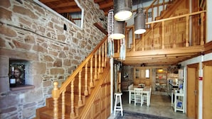A spacious interior with a stone wall, wooden staircase, and a dining area with a table and chairs.