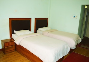 A twin bed room with a wooden headboard, a nightstand, and a red carpet.