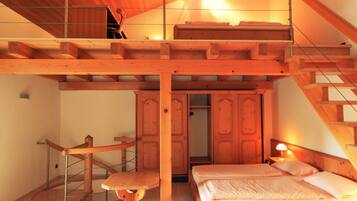 Une chambre aménagée en mezzanine avec un escalier en bois, un lit, un bureau et une chaise.