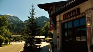 A hotel with a mountain backdrop, a wooden facade, and a clear sky. - Hotel Königsseer Hof (Schoenau am Koenigssee)
