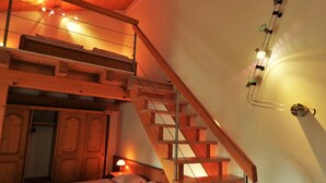 A room with a wooden staircase, a bed, and a wall-mounted light fixture. - Hotel Königsseer Hof (Schoenau am Koenigssee)