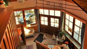 A wooden interior with a staircase, large windows, and a view of the outside. - Hotel Königsseer Hof (Schoenau am Koenigssee)