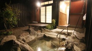 A hot spring area with a wooden bench and a stone pathway leading to a wooden door. - Yufuin Ryoan Wazanhou (Yufu)