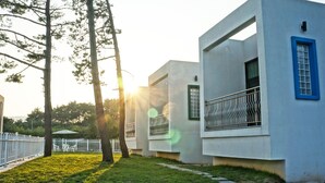A modern building with a flat roof, large windows, and a blue-framed window. - Sea & Pine Pension (Namhae)