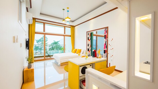 A modern hotel room with a bed, a desk, and a balcony. - Sea & Pine Pension (Namhae)