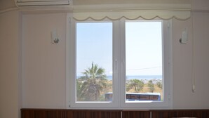 Una habitación con un amplio ventanal que ofrece vistas al mar y palmeras.