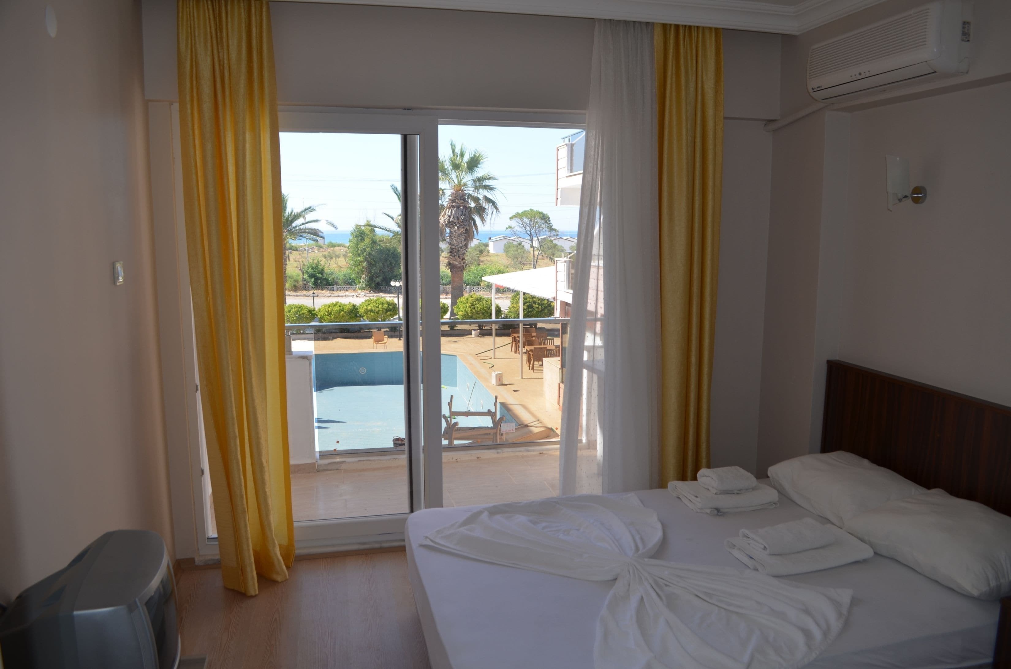 Une chambre d’hôtel équipée d’un lit, d’une télévision et offrant une vue sur une piscine et un espace extérieur aménagé.