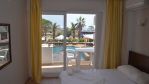 Una habitación de hotel con cama, vista a una piscina y cortinas amarillas.
