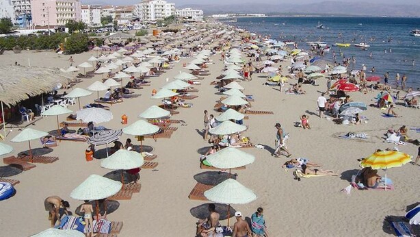 Una playa con numerosas sombrillas y tumbonas, indicando un ambiente de complejo turístico.