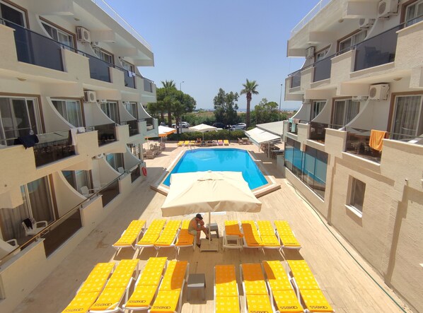 A pool area with yellow lounge chairs and a covered seating area. - Mulka Hotel (Ayvalik)