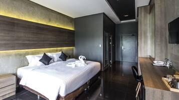 Una habitación de hotel moderna con una cama grande, un cabecero de madera, un escritorio empotrado y un espejo.