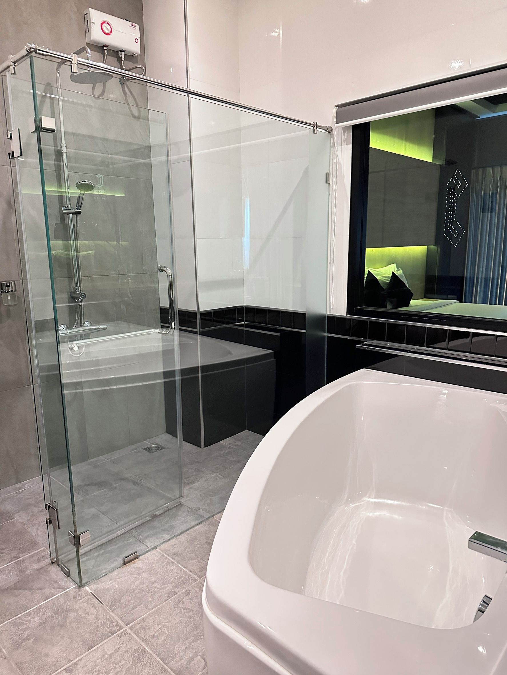 Un baño moderno con ducha de vidrio, bañera blanca y un espejo grande.