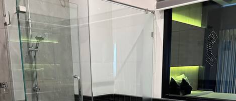 Un baño moderno con ducha de vidrio, bañera blanca y un espejo grande.