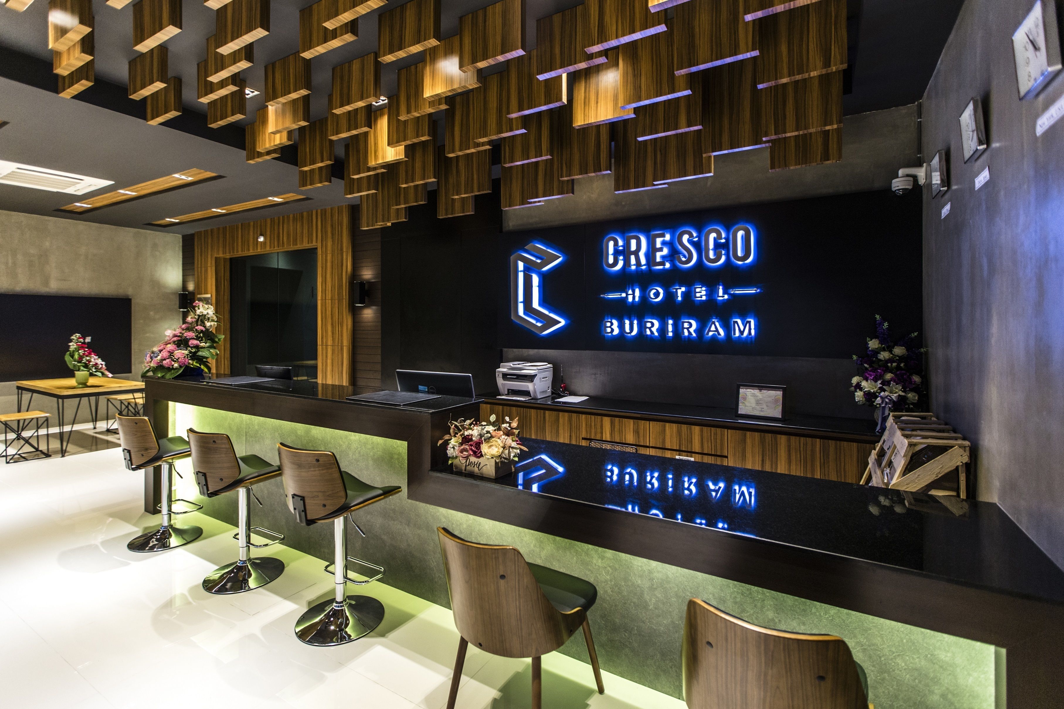A hotel reception area with a modern design, featuring a reception desk, seating area, and a large illuminated sign displaying the hotel name.