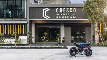 Entrada moderna de un hotel con una motocicleta estacionada frente a él.