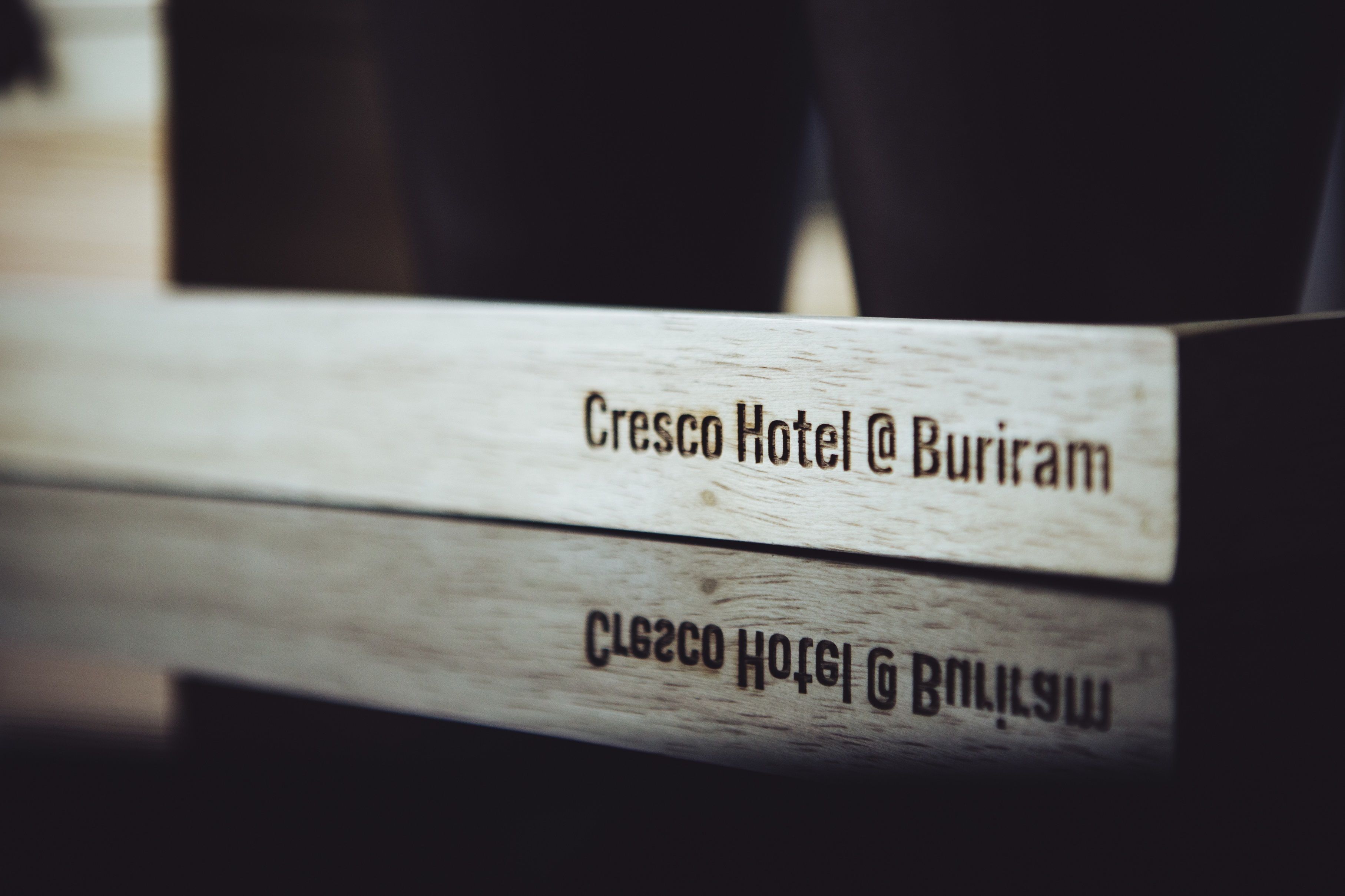 A wooden sign with the text "Cresco Hotel @ Buriram" indicating the hotel's name and location.