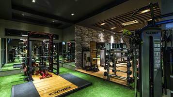 A gym with various exercise equipment, a wooden platform, and a Cybex machine.