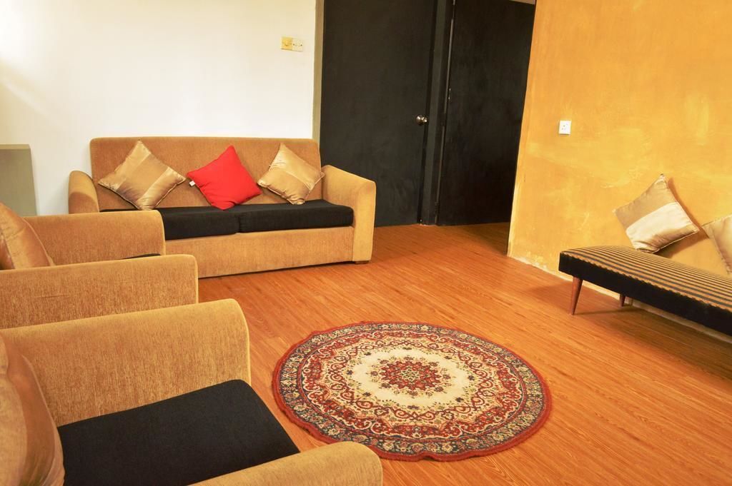 A living room with a beige sofa, a black sofa, and a patterned rug.