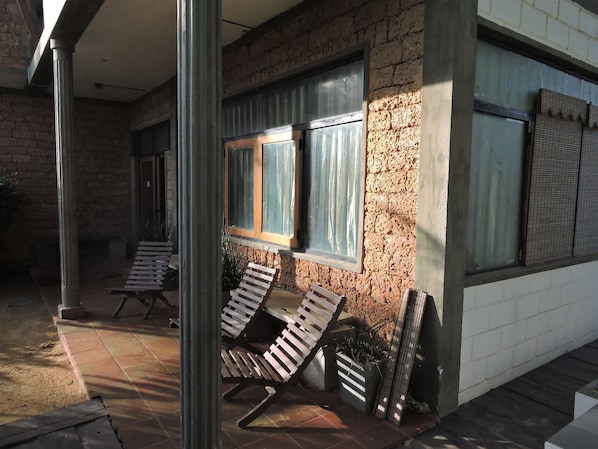 Fachada de un edificio con paredes de ladrillo, ventanas grandes con cortinas y asientos al aire libre.