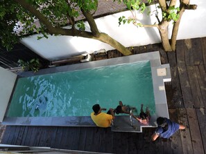 Una piscina rectangular con una cubierta de madera alrededor.