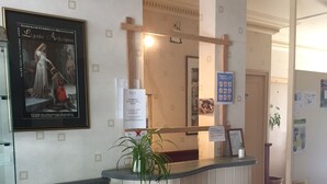 Una zona de recepción con un cuadro histórico enmarco, una planta en maceta y carteles informativos.