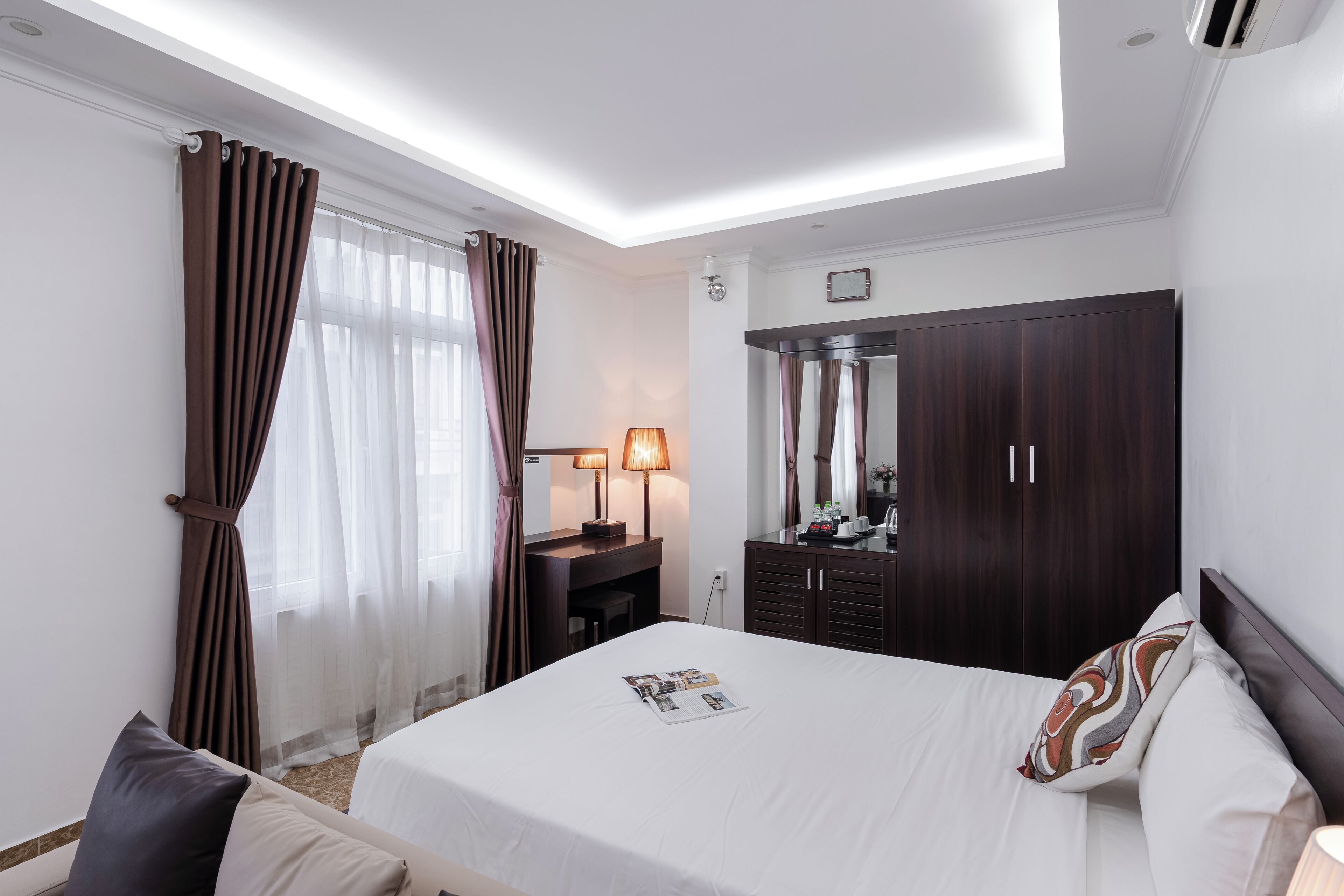 A hotel room with a bed, a desk, a wardrobe, and a mirror.
