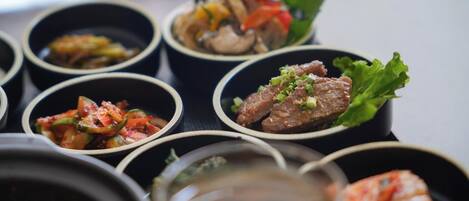 A variety of dishes in small bowls, including what appears to be a meat dish with green onions, a vegetable stir-fry, and a soup.