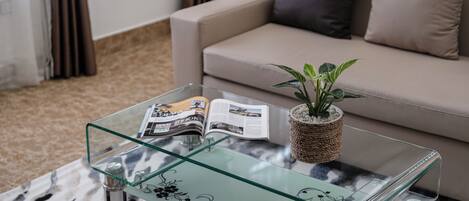 Een glazen salontafel met een tijdschrift, een kleine plant in pot en decoratieve objecten.