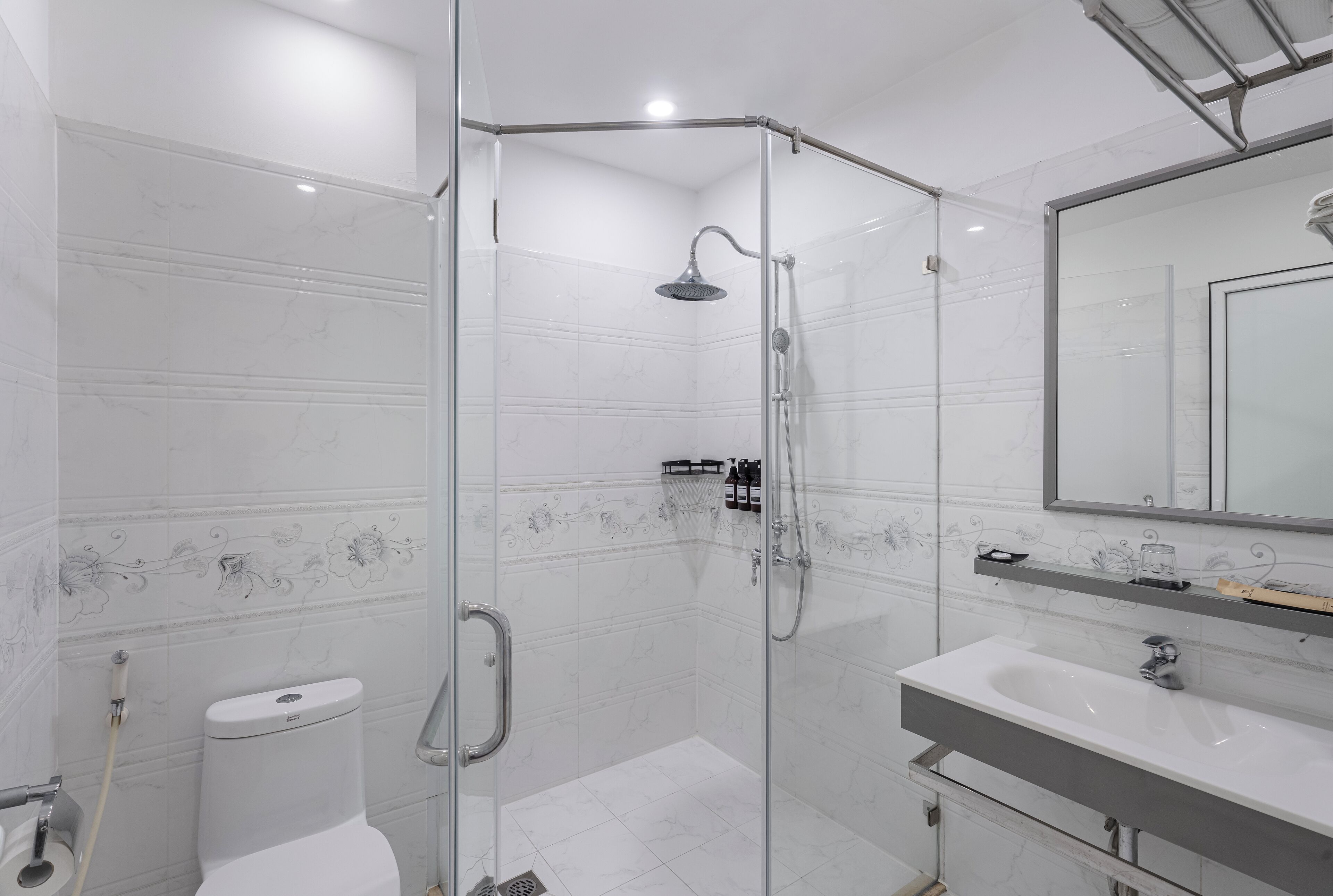 A modern bathroom with a glass-enclosed shower, a white toilet, and a vanity with a mirror.