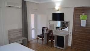 A hotel room with a bed, a desk with a chair, a television, and a door with a mirror. - Megas Hotel (Ayvalik)
