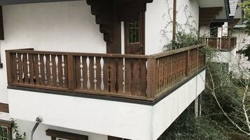 A two-story building with a balcony, a wooden fence, and a garden with hydrangea flowers.
