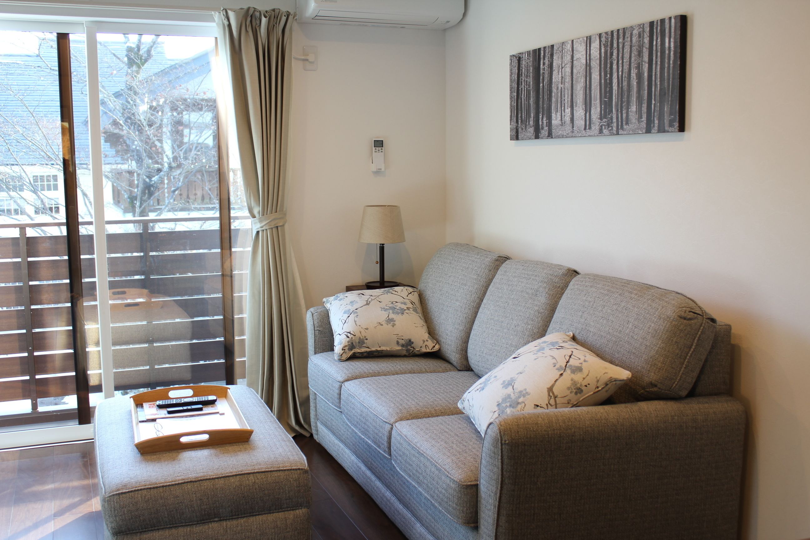 A living room with a sofa, a side table, a lamp, and a painting on the wall.