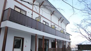 A two-story building with a balcony, large windows, and a snow-covered ground.