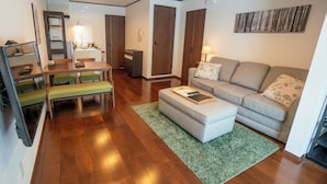 A modern living room with a sofa, a dining table, and a kitchen area in the background.