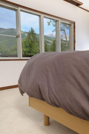 Une chambre à coucher avec un lit, une grande fenêtre et une vue sur un paysage montagneux.