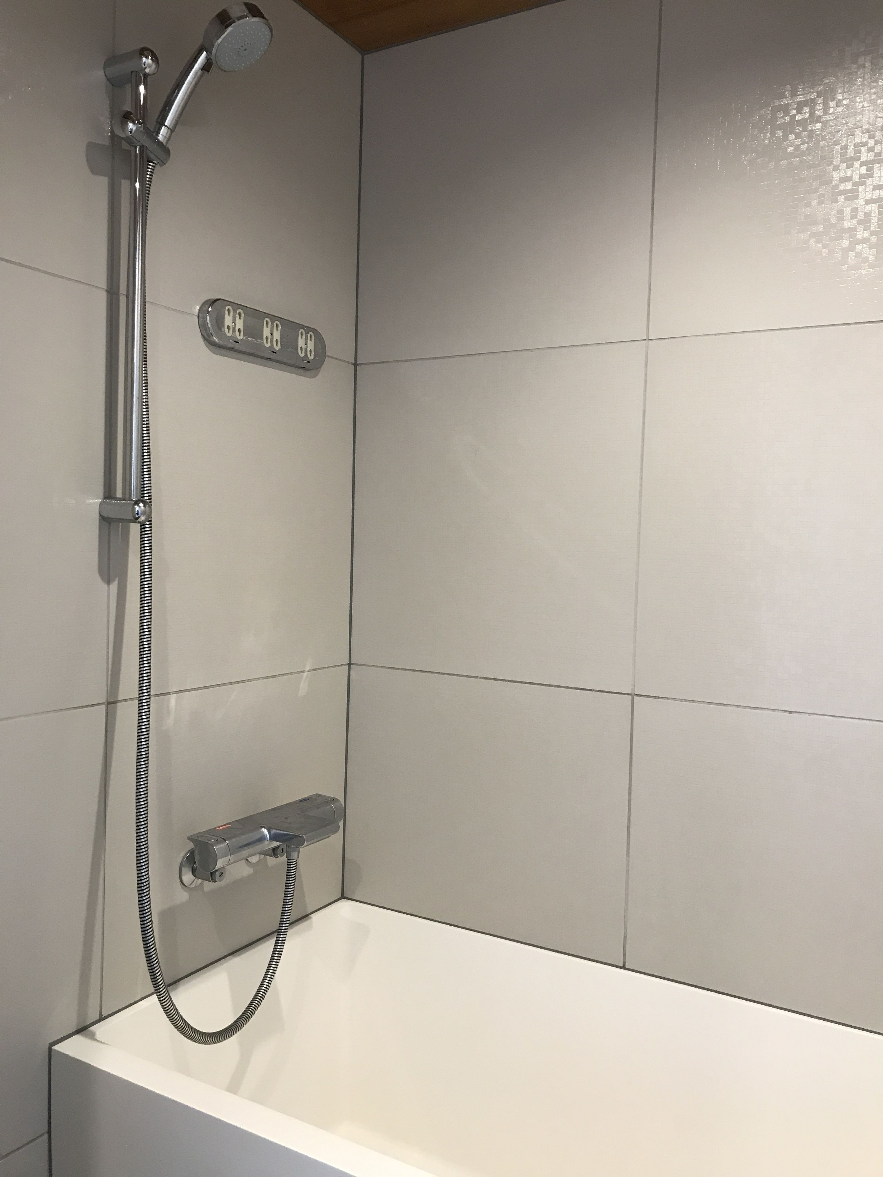 A modern bathroom with a shower, a digital water temperature display, and a handheld showerhead.