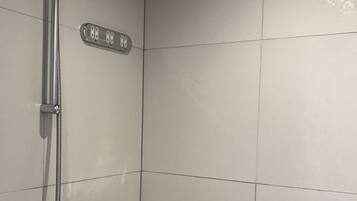 A modern bathroom with a shower, a digital water temperature display, and a handheld showerhead.