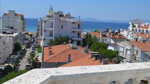 A coastal town with buildings, a clear sky, and the sea in the background. - Kalif Hotel (Ayvalik)