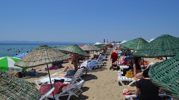 A beach with sun loungers and umbrellas, a clear sky, and the sea in the background. - Kalif Hotel (Ayvalik)