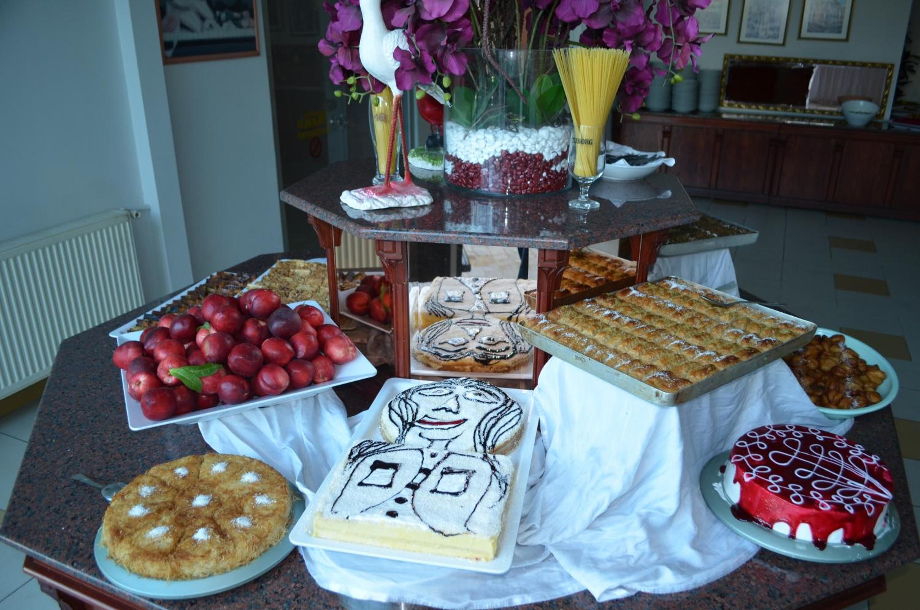 Ein Tisch mit verschiedenen Desserts und Früchten, darunter ein Kuchen mit Gesichtsdesign, ein roter Kuchen und eine Schale Erdbeeren.
