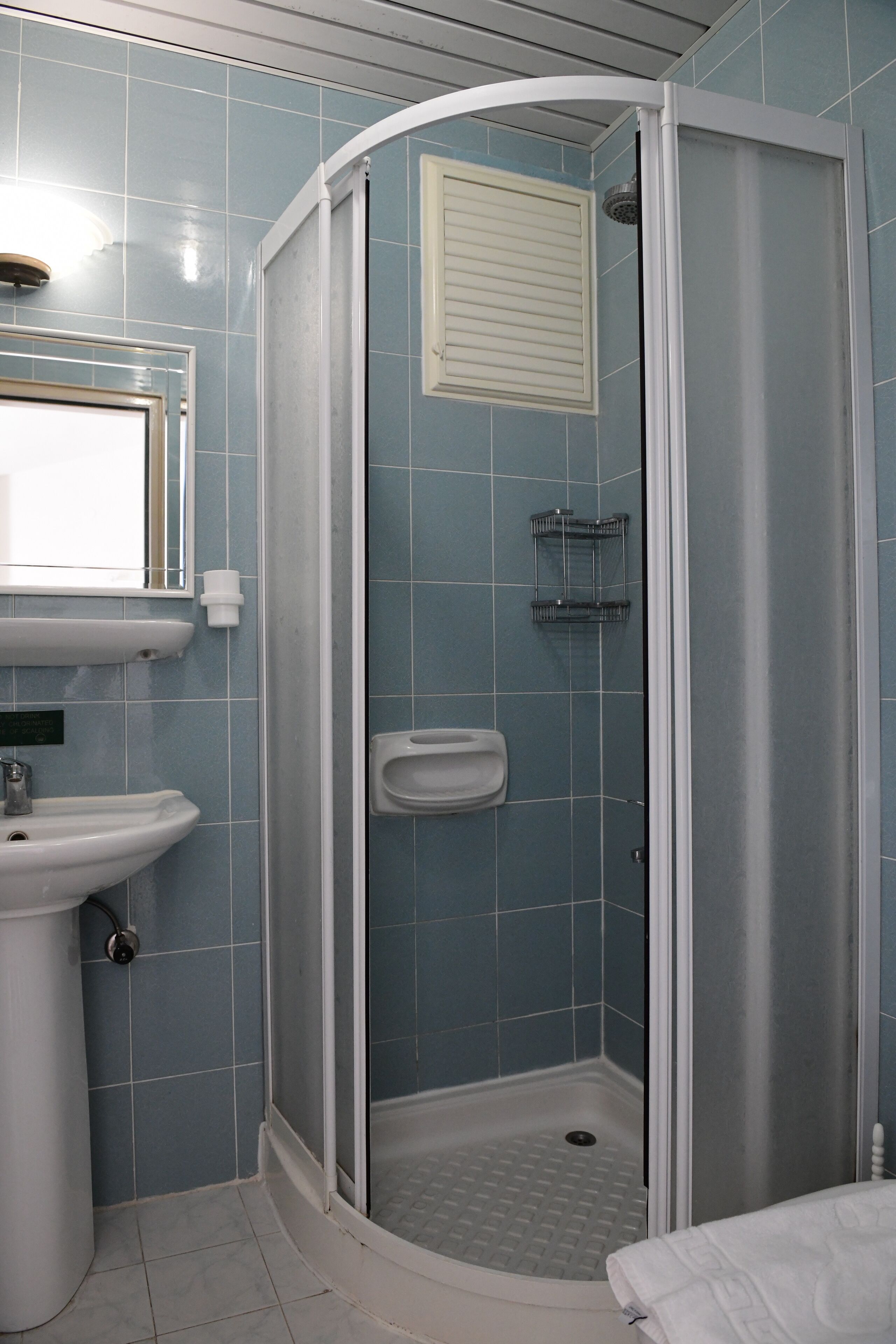 A bathroom with a shower, sink, and mirror.