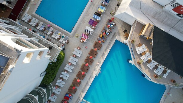 An aerial view of a hotel with two swimming pools, arranged seating areas, and a covered walkway. - Club Atrium Marmaris (Marmaris)