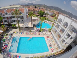 A hotel with a large swimming pool, multiple balconies, and a view of the surrounding town and mountains. - Club Atrium Marmaris (Marmaris)