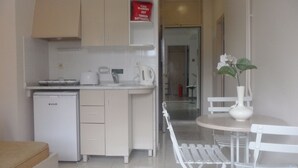 A compact kitchen with a refrigerator, a coffee maker, and a microwave. There is a dining area with a white table and chairs, and a vase with flowers on the table. - Club Atrium Marmaris (Marmaris)