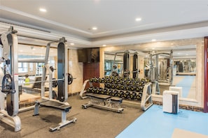 A gym with various exercise equipment, including weight machines, dumbbells, and a treadmill.