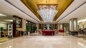 A spacious lobby with a grand chandelier, a reception desk, and a seating area with red sofas. - Qianjiang Junting Hotel, Haining (Jiaxing)